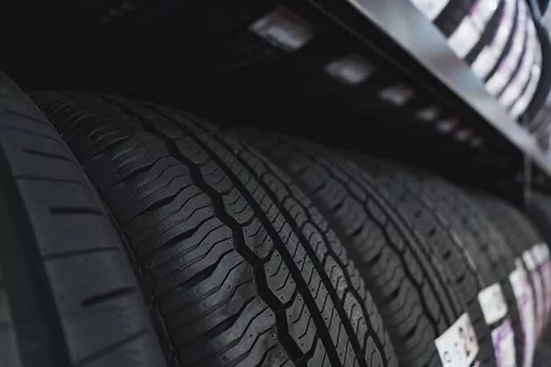 Mehrere Autoreifen mit deutlichem Profil sind in einem Regal eines Reifenlagers aufgereiht.