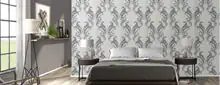 Modern eingerichtetes Schlafzimmer mit gemusterter Tapete in Grau-Weiß, einem Doppelbett mit grauer Decke und zwei Nachttischen mit Lampen.