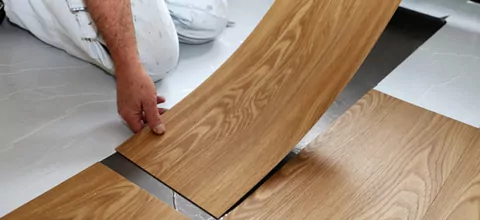 Ein Mann kniet auf dem Boden und verlegt PVC-Boden.